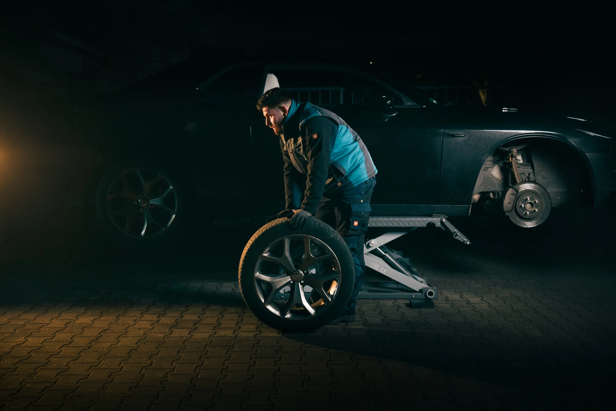 Radek beim Radwechsel am angehobenen Pkw mit Scherenhebebühne